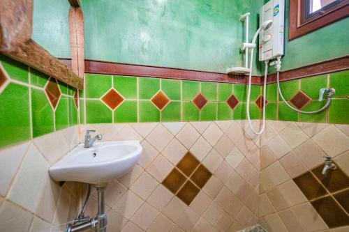 a bathroom with a sink and green and brown tiles at มนต์เมืองเชียงใหม่ รีสอร์ต Monmuang Chiangmai Resort in Hang Dong