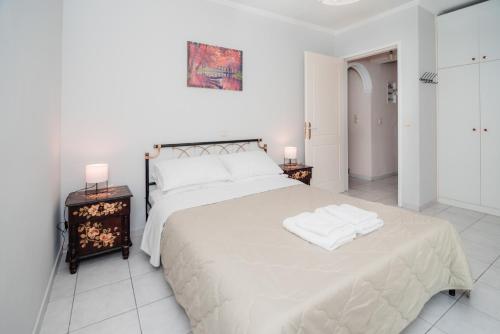 ein weißes Schlafzimmer mit einem großen Bett mit zwei Nachttischen in der Unterkunft Anna Maria house in Perama