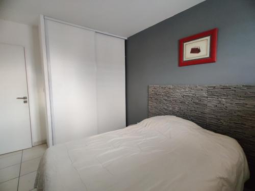 une chambre avec un lit blanc et un mur de briques dans l'établissement Le Village 76 m2 Climatisation 1er arrondissement gare à pied, à Marseille