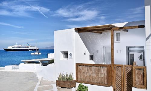 ein weißes Haus mit einem Kreuzfahrtschiff im Hintergrund in der Unterkunft Little Venice Suites in Mykonos Stadt