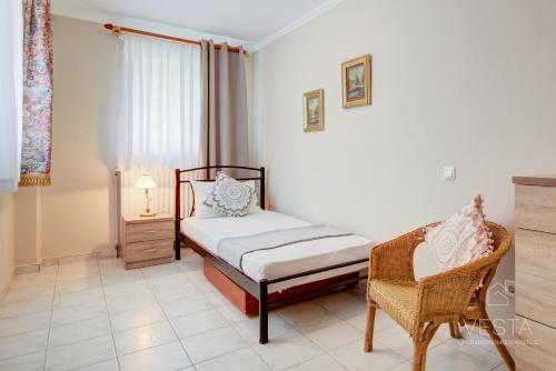 a bedroom with a bed and a chair at Private 6-bdrm Villa with garden 150m to beach in Paradisos