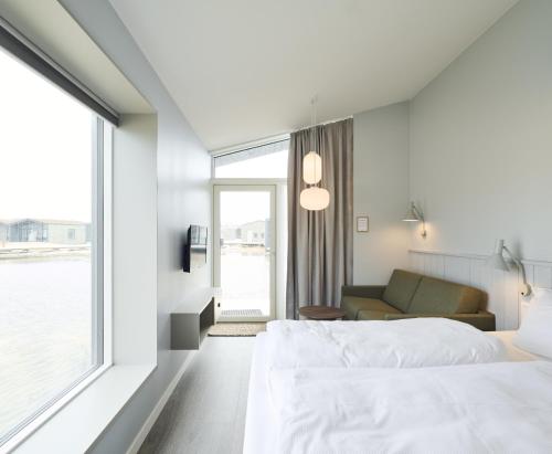 a bedroom with a bed and a couch and a window at Hages Badehotel in Rødby