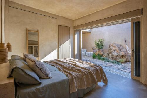 a bedroom with a large bed with a large window at Homa Serifos pool villas in Serifos Chora