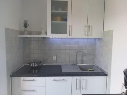 a kitchen with white cabinets and a sink at Apartments Vila Ana in Seline