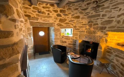 Habitación con pared de piedra y chimenea. en MOULIN DE KERNOT, en Cléden-Cap-Sizun