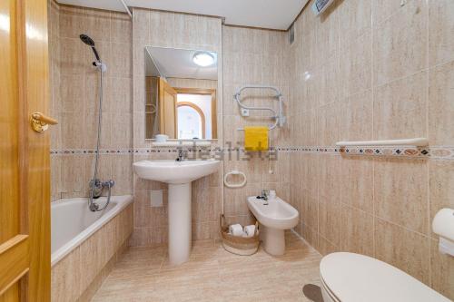 a bathroom with a sink and a toilet and a mirror at Aguamarina Playa in Orihuela