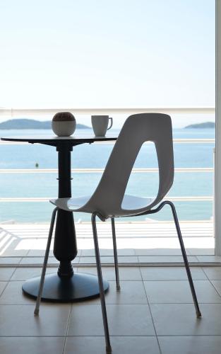 a white chair sitting next to a glass table at Anemoni Beach Hotel in Skiathos Town