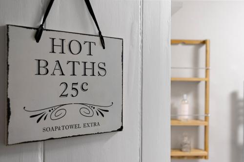 ein Schild mit der Aufschrift „Heiße Bäder“ hängt an der Wand in der Unterkunft Pip's Cottage by Staytor Accommodation in Exeter