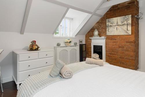 a bedroom with a white bed and a brick wall at Pip's Cottage by Staytor Accommodation in Exeter