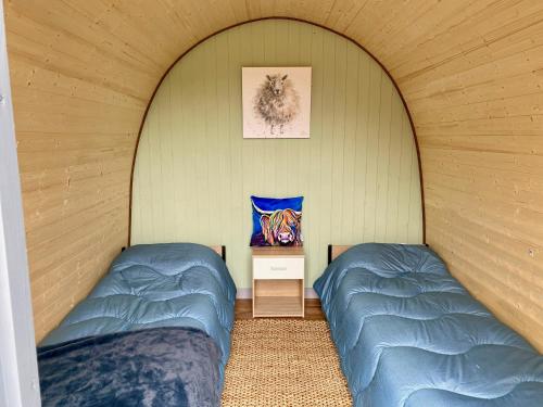 two beds in a room with an archway at MotoCamp Wales -Camping Pods in Dolgellau