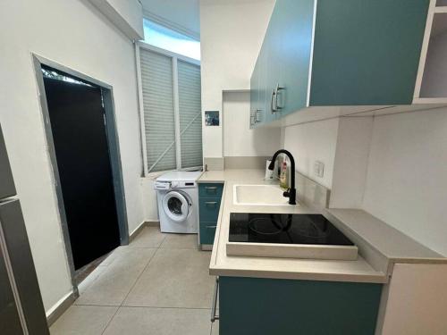 een keuken met een wastafel en een wasmachine bij Apartment with terrace sea view in Haifa