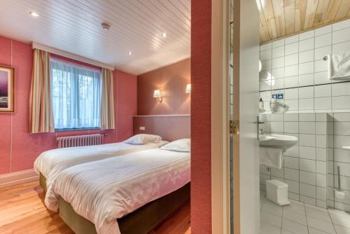 1 dormitorio con 1 cama y baño en Hôtel Le Cor de Chasse en Saint-Hubert