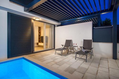 une terrasse avec une piscine, 2 chaises et une table dans l'établissement ChillZone - 20m to the sea, heated pool, à Trogir