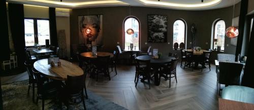 a restaurant with tables and chairs in a room with windows at 3 Monkeys Hotel in Steinfurt