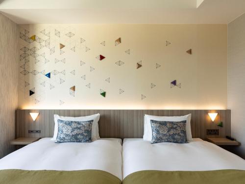 una camera con due letti e una parete con farfalle di Tokyu Stay Kanazawa a Kanazawa