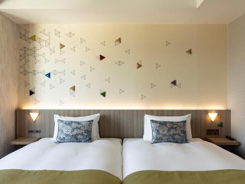 a bedroom with two beds and a wall with butterflies at Tokyu Stay Kanazawa in Kanazawa