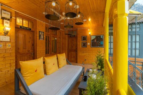 a room with a bed with yellow pillows at Whoopers Boutique Kasol in Kasol