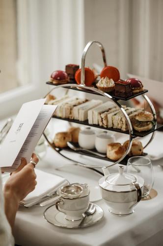 a person holding a piece of paper next to a tray of food at The Roseate Villa Bath in Bath