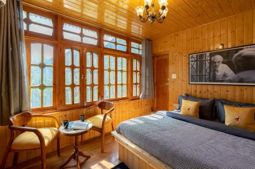 Schlafzimmer mit einem Bett, einem Tisch und Fenstern in der Unterkunft Whoopers Boutique Kasol in Kasol