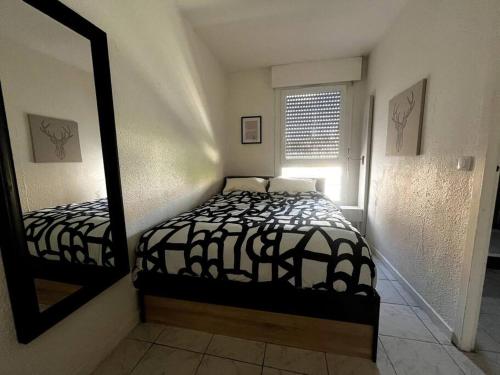 une petite chambre avec un lit et un miroir dans l'établissement Joli appartement T2 centre port avec wifi, au Cap d'Agde