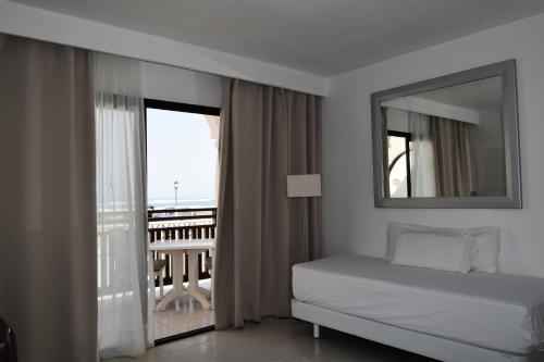 1 dormitorio con cama, espejo y balcón en Apartamentos Hesperia Bristol Playa, en Corralejo