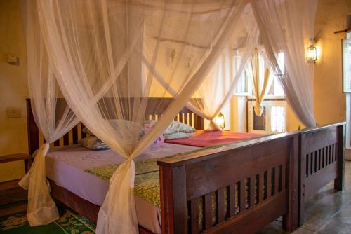 a bedroom with a wooden bed with a canopy at Firefly Boutique Lodge in Bagamoyo