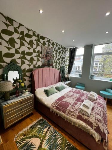 a bedroom with a pink bed and a patterned wall at flat Covent Garden in London