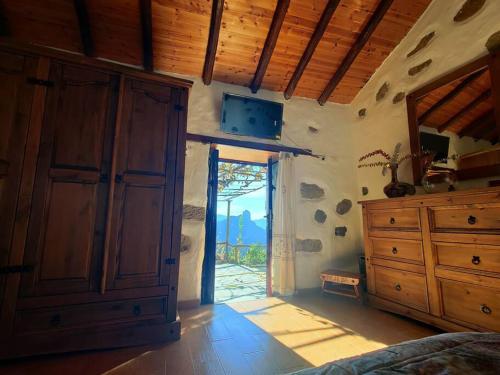 a bedroom with a large wooden cabinet and a sliding glass door at Finca Ancestros in Tejeda