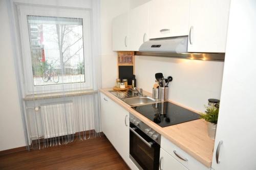 uma cozinha com armários brancos, um lavatório e uma janela em WG Zimmer in der World of Living K em Regensburg