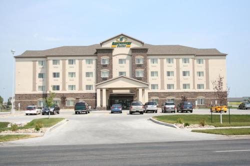 a large building with cars parked in a parking lot at Expressway Suites Fargo in Fargo
