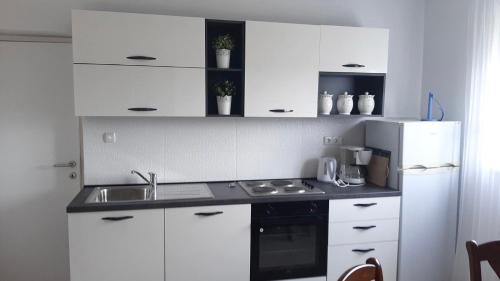 a kitchen with white cabinets and a sink and a refrigerator at Apartment Tea in Rab