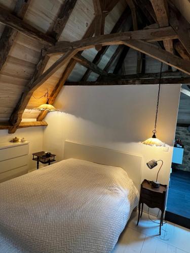 une chambre avec un lit blanc et des plafonds en bois dans l'établissement La grange de Mimi, à Fourmagnac