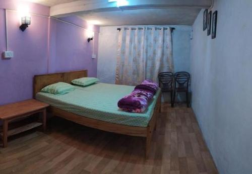 a bedroom with a bed with a purple blanket on it at Hunsi Homestay in Sohrārim