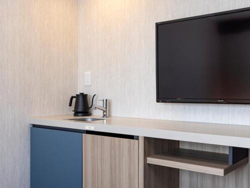 a flat screen tv sitting on a wall next to a sink at Tokyu Stay Kanazawa in Kanazawa