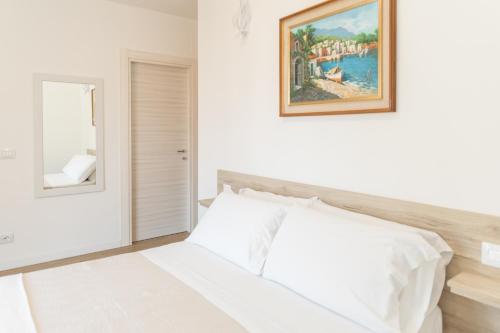 een slaapkamer met een wit bed en een schilderij aan de muur bij B&B Dal Maestro in Maratea