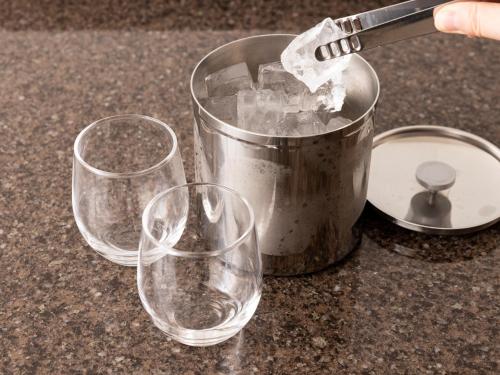 three wine glasses sitting next to a bucket on a counter at Tokyu Stay Kanazawa in Kanazawa