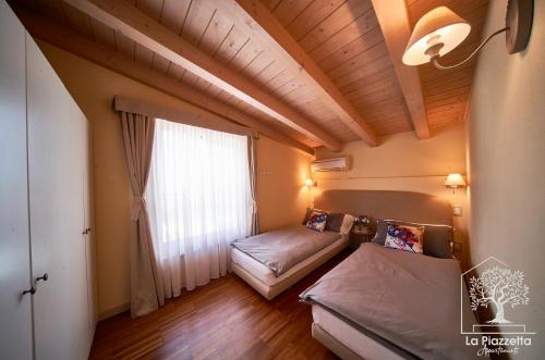 西爾米奧奈的住宿－Appartamenti La Piazzetta，客房设有两张床和大窗户。