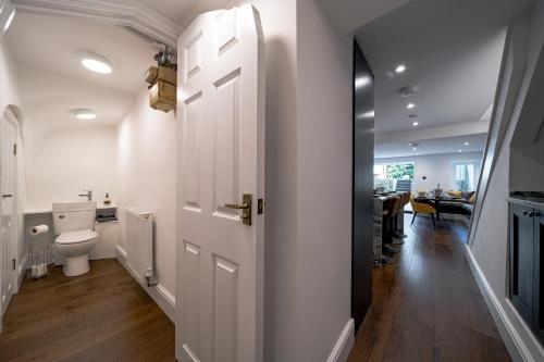 a white bathroom with a toilet and a hallway at Luxurious GRAND 6 BR Home in BATH - Perfect for Groups & Sleeps 12! in Bath