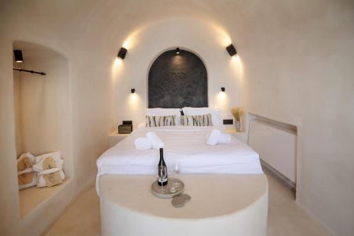 a bedroom with a large white bed with a window at One of One - Aether in Oia