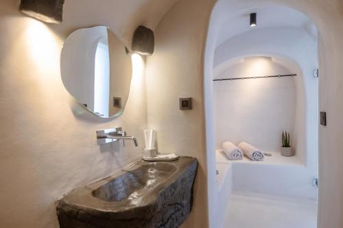 a bathroom with a stone sink and a mirror at One of One - Aether in Oia