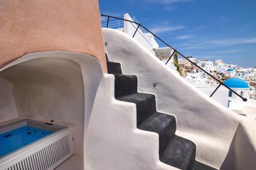 a staircase leading up to a building with a swimming pool at One of One - Aether in Oia