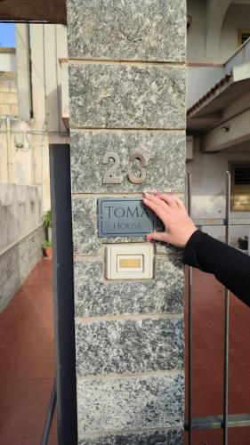 a person holding a sign on a stone wall at ToMa House in Pellaro