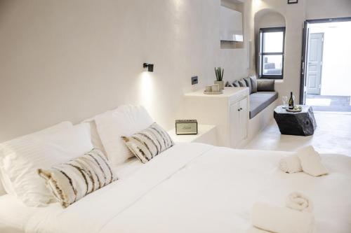 a white bedroom with a large white bed and a couch at One of One - Aurelia in Oia
