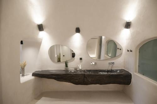 a bathroom with a sink and two mirrors at One of One - Aurelia in Oia