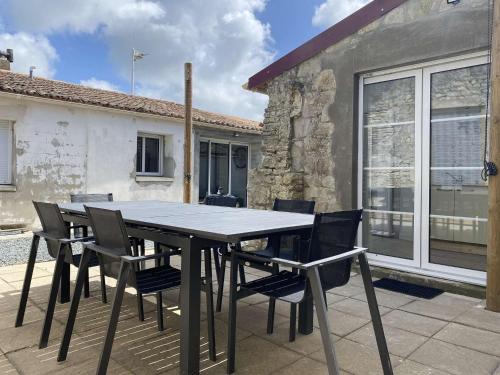 une table noire et des chaises sur une terrasse dans l'établissement Maison rénovée 4 pièces, 6 couchages, terrasse, proche commerces et plages - Saint-Pierre-d'Oléron - FR-1-246A-215, à Saint-Pierre-dʼOléron