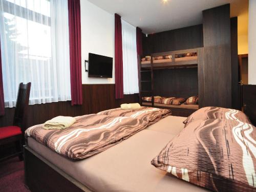 a bedroom with two beds and a tv in it at Penzion Budopartner in Jívka