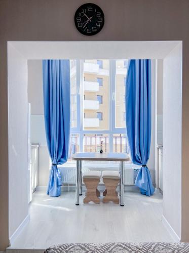 a dining room with a table and blue curtains at Лайт студия Вокзал Харьков-Пассажирский in Kharkiv