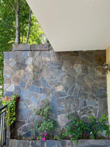 a stone retaining wall with flowers and plants at Ortus - Murree Hills in Murree