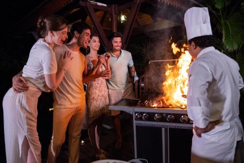 a group of people standing in front of a grill at JA Enchanted Island Resort Seychelles in Round Island