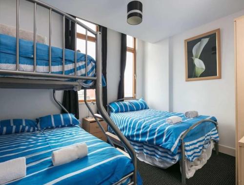 two beds in a room with blue and white sheets at City centre apartment with view in Manchester